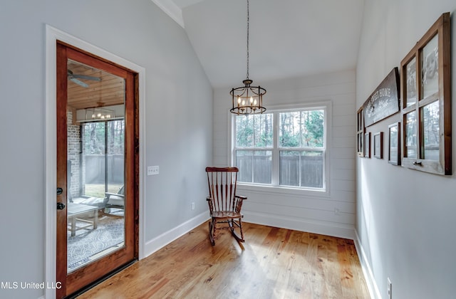 living area with an inviting chandelier, vaulted ceiling, and light hardwood / wood-style floors