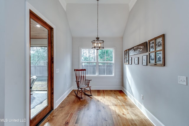 dining area featuring lofted ceiling, light hardwood / wood-style flooring, a healthy amount of sunlight, and an inviting chandelier