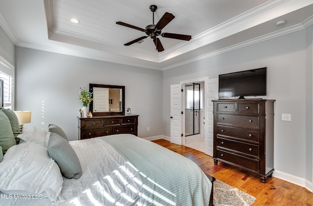 bedroom featuring ornamental molding, light hardwood / wood-style flooring, ceiling fan, and a tray ceiling