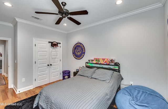 bedroom featuring hardwood / wood-style flooring, ceiling fan, crown molding, and a closet