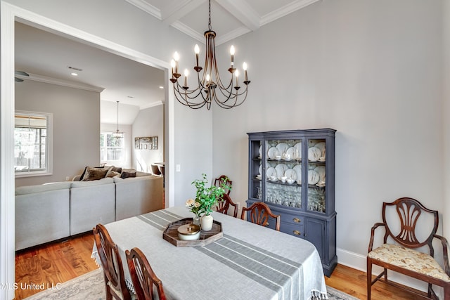 dining space with ornamental molding, coffered ceiling, and light wood-type flooring