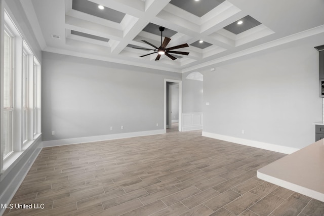 empty room featuring beam ceiling, light wood-type flooring, ceiling fan, coffered ceiling, and crown molding