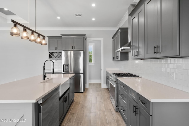 kitchen with gray cabinetry, sink, light hardwood / wood-style floors, stainless steel appliances, and decorative light fixtures