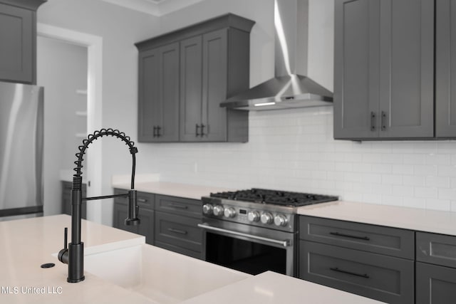 kitchen with gray cabinetry, wall chimney exhaust hood, and appliances with stainless steel finishes