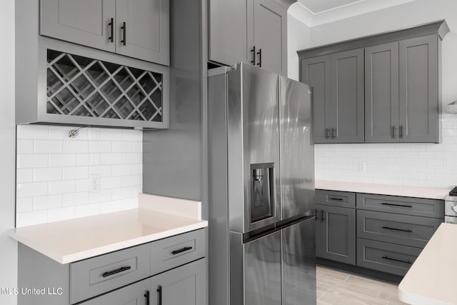 kitchen featuring appliances with stainless steel finishes, light wood-type flooring, backsplash, and gray cabinetry