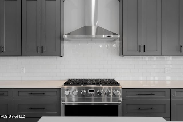 kitchen with wall chimney exhaust hood, gray cabinets, and high end stove