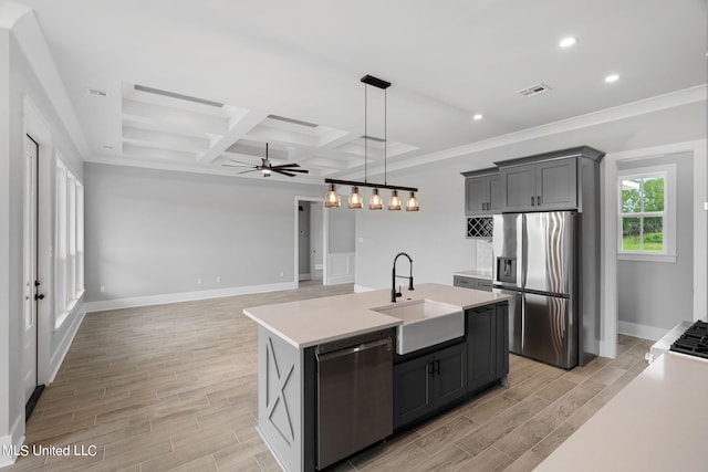 kitchen featuring a kitchen island with sink, light wood-type flooring, stainless steel appliances, sink, and coffered ceiling