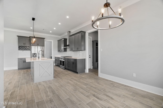 kitchen featuring appliances with stainless steel finishes, decorative light fixtures, gray cabinets, light hardwood / wood-style flooring, and a center island with sink