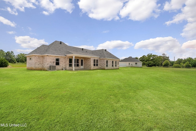 rear view of property featuring a patio area, central AC, and a lawn