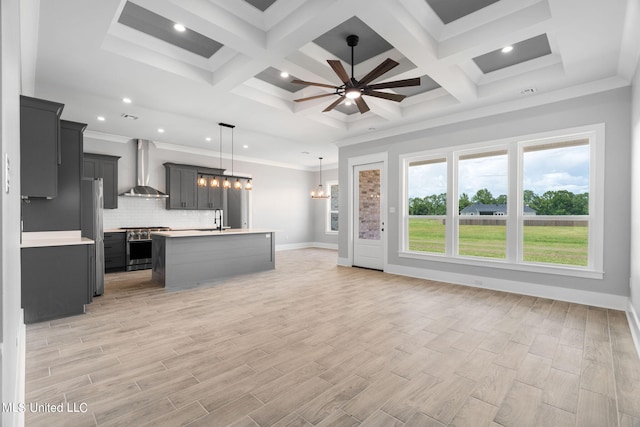 unfurnished living room with sink, coffered ceiling, ceiling fan with notable chandelier, and light hardwood / wood-style floors