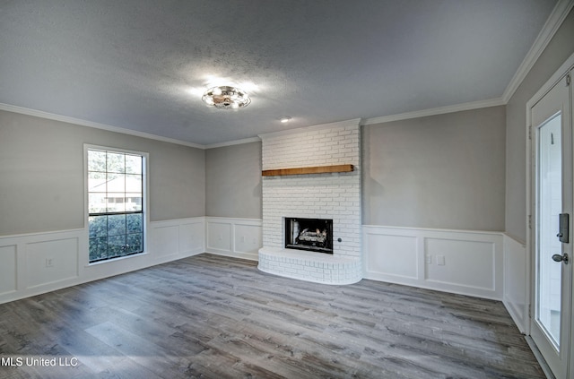 unfurnished living room featuring crown molding, a textured ceiling, a brick fireplace, and hardwood / wood-style floors