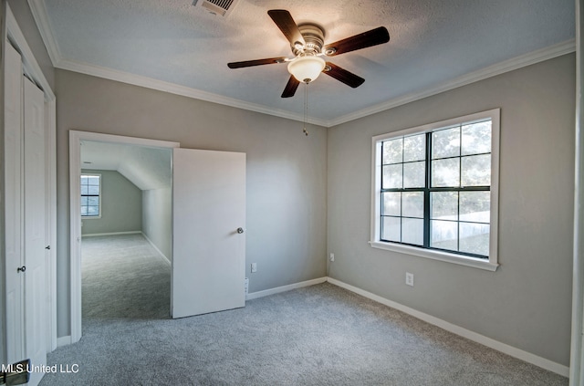 empty room featuring a wealth of natural light, a textured ceiling, crown molding, and light colored carpet