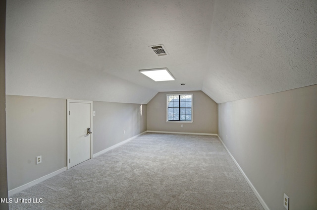 bonus room featuring a textured ceiling, light colored carpet, and vaulted ceiling