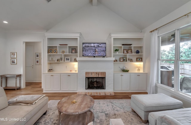 living room featuring a fireplace, lofted ceiling, and light hardwood / wood-style flooring