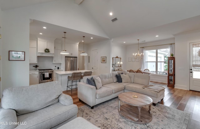 living room featuring high vaulted ceiling, light hardwood / wood-style flooring, beamed ceiling, and a chandelier