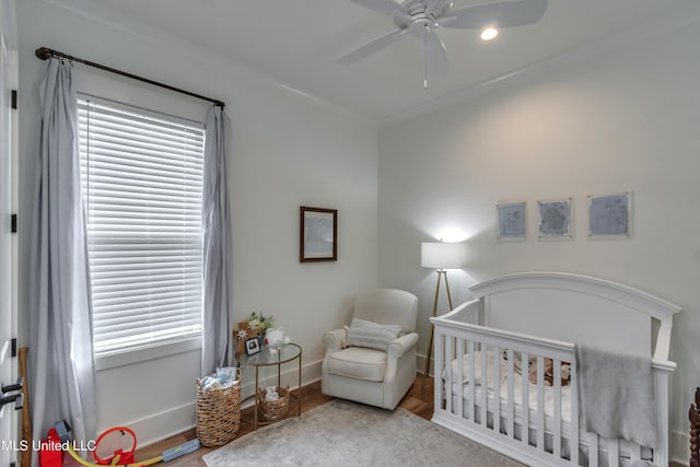 bedroom featuring a crib, hardwood / wood-style flooring, and ceiling fan