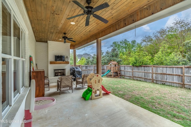 view of patio / terrace featuring a fireplace, ceiling fan, and a playground