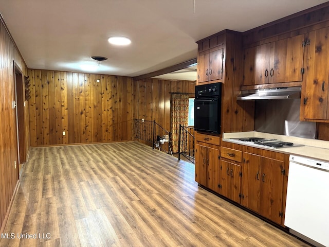 kitchen with white dishwasher, light wood-style flooring, oven, under cabinet range hood, and stovetop with downdraft