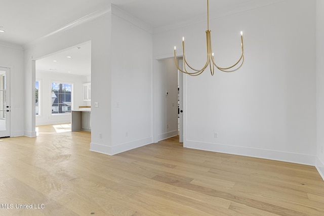 empty room with crown molding, an inviting chandelier, and light hardwood / wood-style flooring