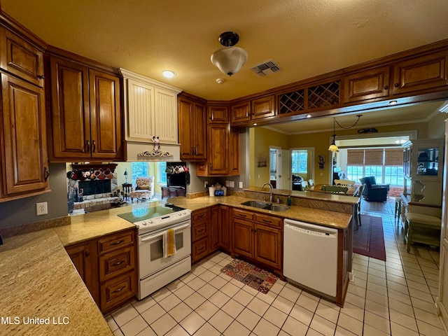 kitchen featuring kitchen peninsula, pendant lighting, crown molding, sink, and white appliances