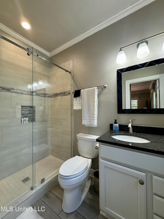 bathroom featuring vanity, toilet, crown molding, and a shower with shower door