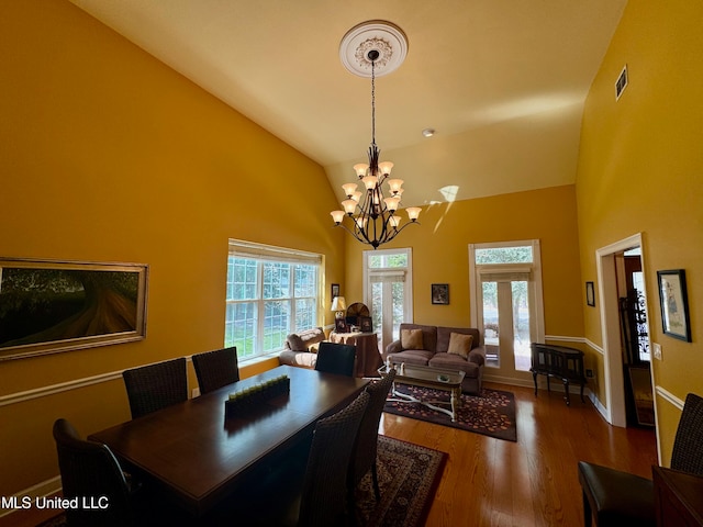 dining space with a chandelier, hardwood / wood-style floors, high vaulted ceiling, and french doors