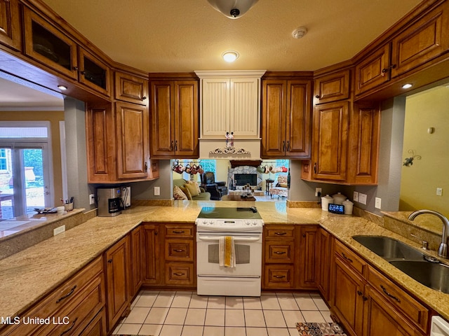 kitchen featuring sink, kitchen peninsula, white range with electric cooktop, light stone counters, and light tile patterned floors