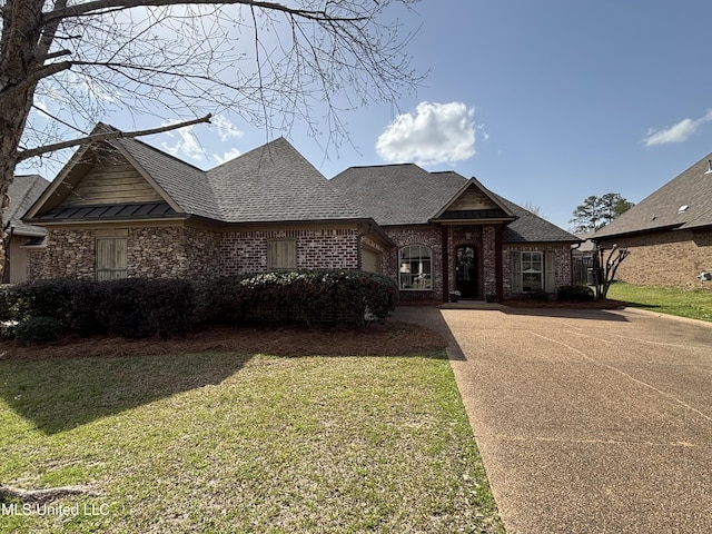 french provincial home with a front yard, driveway, roof with shingles, an attached garage, and brick siding