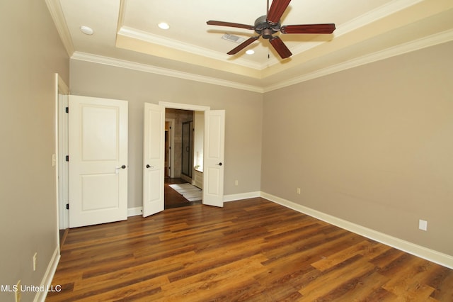 unfurnished bedroom with visible vents, crown molding, baseboards, a tray ceiling, and dark wood-style floors