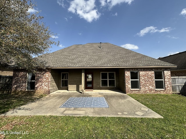 back of property with brick siding, a patio, a lawn, and fence