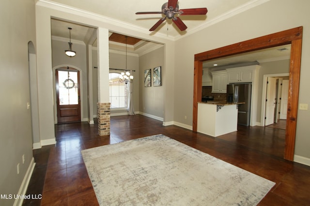 foyer entrance featuring arched walkways, ceiling fan with notable chandelier, crown molding, and baseboards