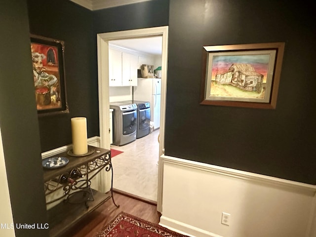 hall featuring separate washer and dryer, crown molding, and hardwood / wood-style floors