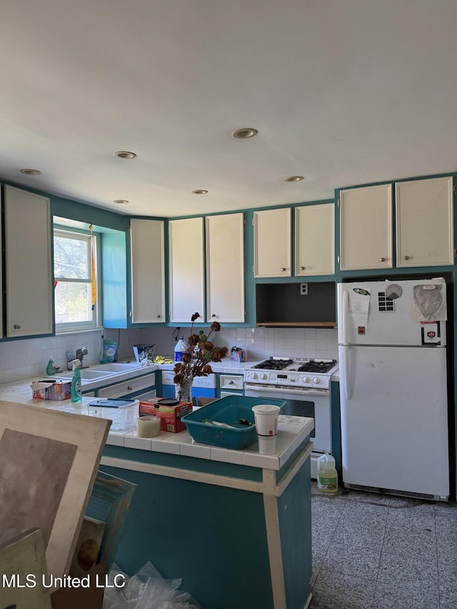 kitchen with recessed lighting, granite finish floor, backsplash, white cabinetry, and white appliances