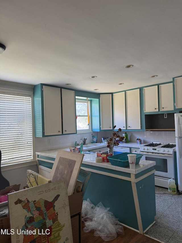 kitchen featuring white appliances, white cabinetry, light countertops, and backsplash