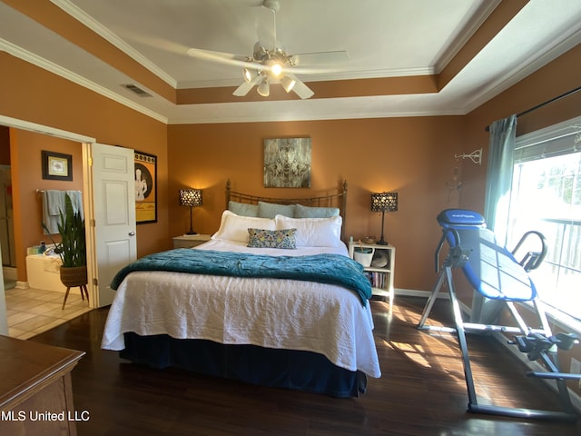 bedroom with a raised ceiling, crown molding, wood finished floors, and visible vents