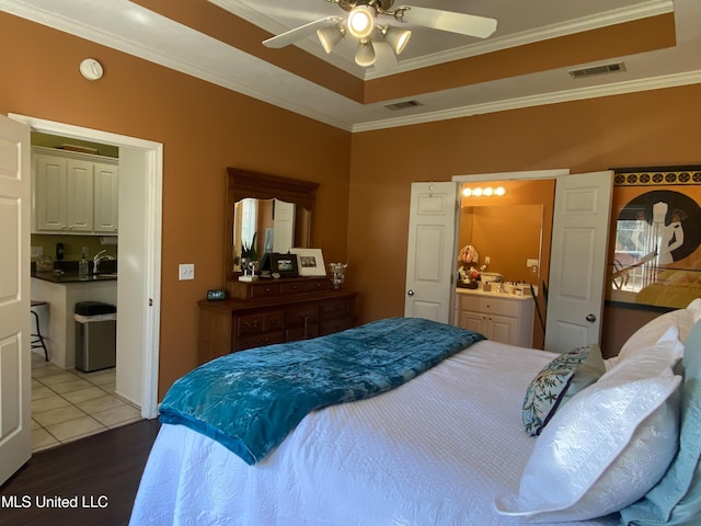 bedroom with a raised ceiling, wood finished floors, visible vents, and ornamental molding