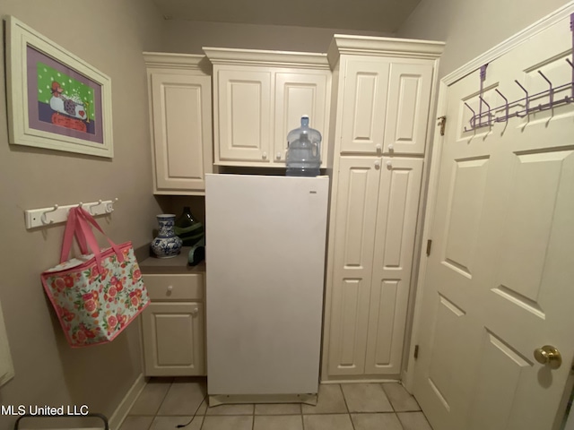 kitchen featuring light tile patterned floors, white cabinetry, and freestanding refrigerator