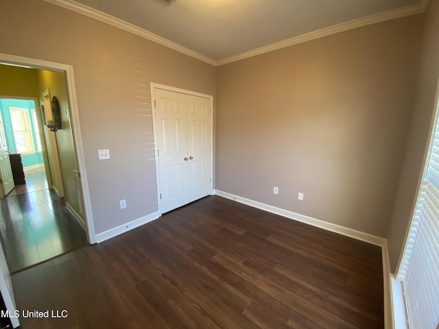 unfurnished bedroom featuring baseboards, dark wood-style flooring, a closet, and ornamental molding