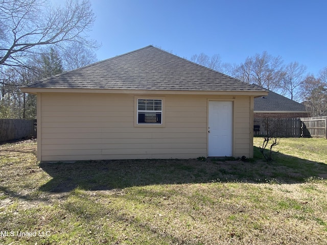 rear view of property featuring a yard, roof with shingles, and fence