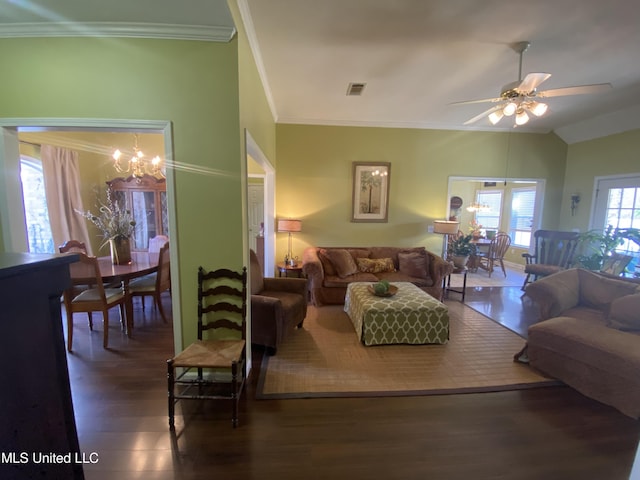 living room with visible vents, ceiling fan with notable chandelier, wood finished floors, crown molding, and vaulted ceiling