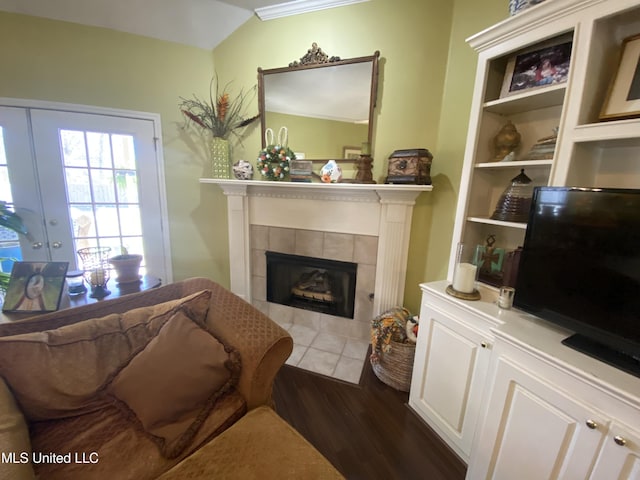 living room featuring dark wood-type flooring, a tiled fireplace, and vaulted ceiling