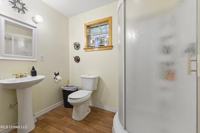 full bathroom featuring a shower stall, toilet, wood finished floors, a sink, and baseboards
