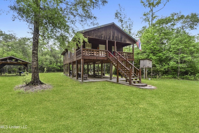 back of house with a carport, a lawn, stairway, a deck, and a patio
