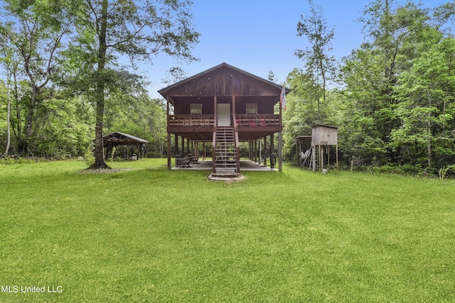 rear view of property with stairway and a yard