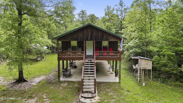 view of front of property with stairway, a forest view, and a patio