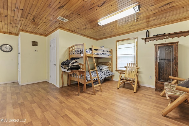 bedroom with baseboards, crown molding, light wood finished floors, and visible vents