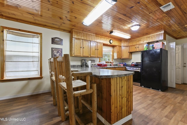 kitchen featuring stainless steel range with gas cooktop, dark countertops, wood ceiling, a peninsula, and freestanding refrigerator