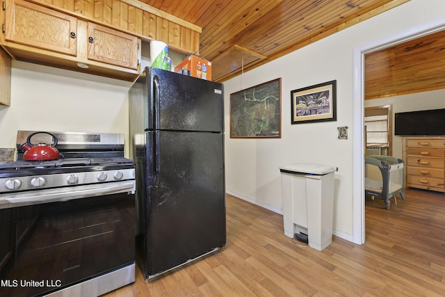 kitchen featuring light wood finished floors, stainless steel range with gas stovetop, wooden ceiling, freestanding refrigerator, and baseboards