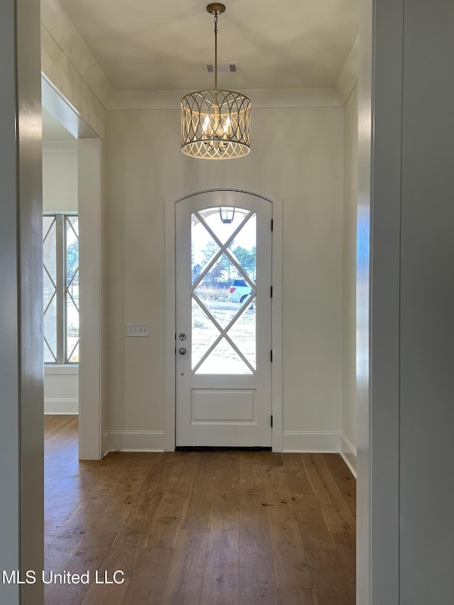 entryway featuring crown molding, wood-type flooring, and a chandelier