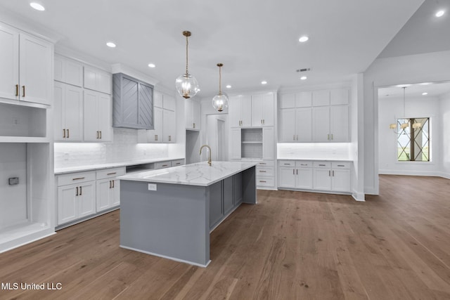 308 Lois Ct, Madison, MS 39110 - kitchen with decorative backsplash, wood finished floors, a kitchen island with sink, white cabinetry, and recessed lighting